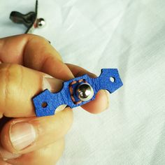 a person holding a small blue object in their left hand and two pairs of scissors on the right