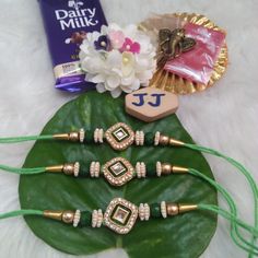 a green leaf with some gold and white beads on it next to other items that are sitting on top of the leaves