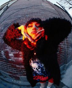 a woman with her hands on her face standing in front of a round brick wall