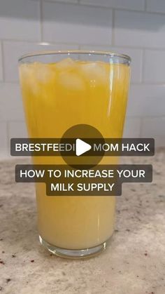 a glass filled with orange juice sitting on top of a counter next to a white tile wall