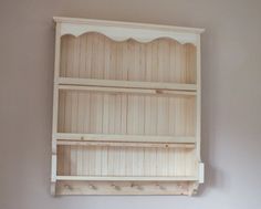 a white shelf with two shelves on top of it in the corner of a room