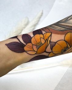 a woman's arm with yellow flowers on it and leaves around the wrist area