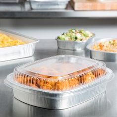 plastic containers filled with food sitting on top of a metal counter next to other dishes