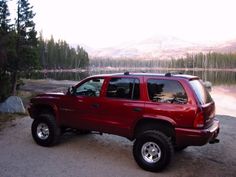 a red pick up truck parked next to a lake