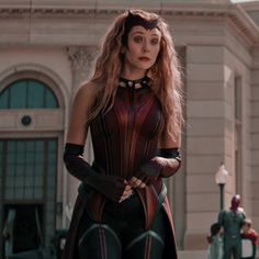 a woman dressed as catwoman stands in front of a building with other people standing around