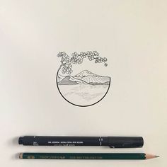 a pencil is sitting next to a drawing of a tree and mountains in the distance