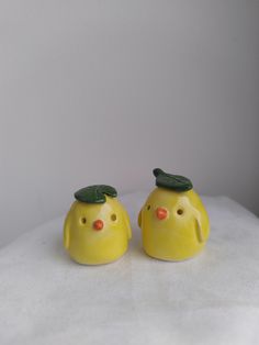 two yellow ceramic birds with green leaves on their heads