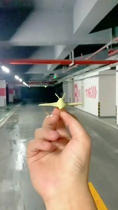 a hand holding a tiny yellow starfish in a parking garage