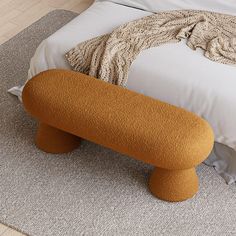 an orange bench sitting on top of a bed in a room with white sheets and pillows