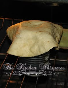 an uncooked tortilla sitting on top of a metal pan in the oven