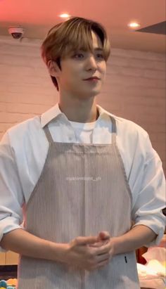 a young man wearing an apron standing in a kitchen