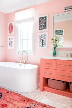 a bathroom with pink walls and white tub in the center, red rug on the floor