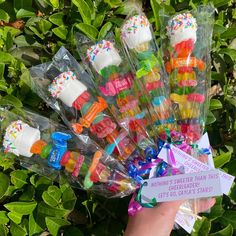 a person holding up a bunch of colorful candy lollipops in plastic wrappers