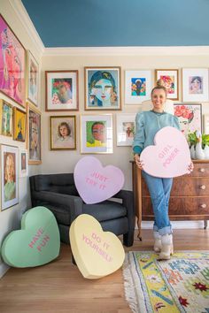 a woman holding two heart shaped signs in her living room