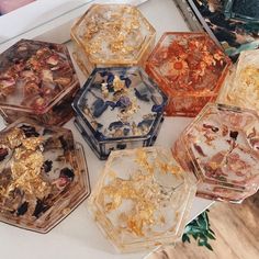 several different colored glass containers with gold flakes in them on a white table top