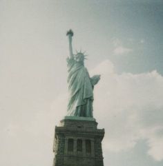 the statue of liberty is shown against a cloudy sky