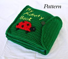 a green crocheted book with a ladybug on it