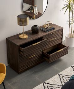 a living room with a large mirror on the wall next to a dresser and chair