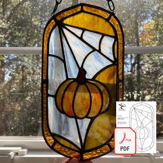 a hand holding up a stained glass window with pumpkins on it and an arrow pointing to the right