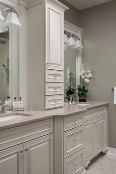 a large bathroom with two sinks and white cabinetry, along with an open shower