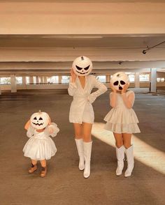 two women in white dresses and one is wearing a ghost mask while the other holds up her hands