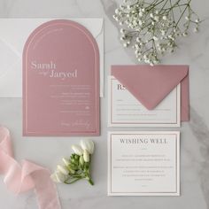 the wedding stationery is laid out on a marble table