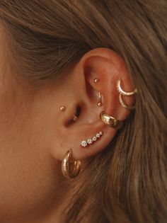 a woman wearing three different types of ear piercings