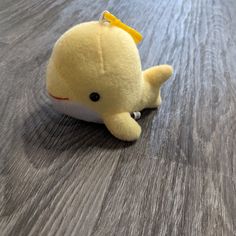 a yellow stuffed animal laying on top of a wooden floor next to a keychain