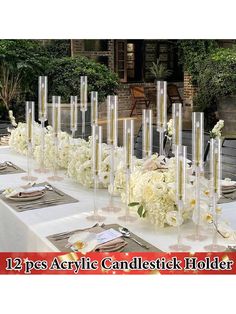 there is a long table with many candles and flowers on it, along with place settings for the centerpieces