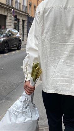 a man holding flowers in his hand on the street