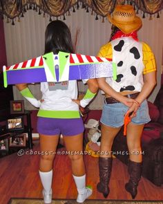 two women dressed in costumes standing next to each other with a toy plane on their back