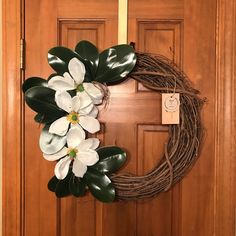 a wreath with white flowers is hanging on the front door to decorate it for someone's special occasion