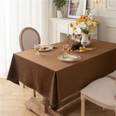 a dining room table set for two with flowers and fruit on the placemats