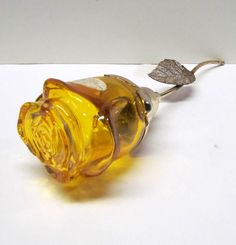 a yellow glass bottle with a leaf on the top is sitting on a white surface