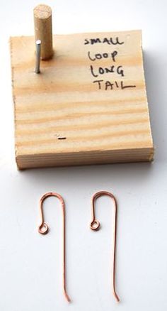 two small hooks are attached to a piece of wood with some writing on the side