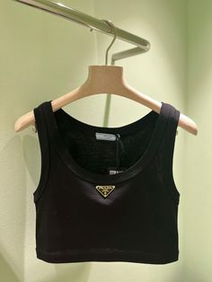 Made from soft cotton jersey, this tank-style crop top is a menswear-inspired design with a feminine touch. This piece features Prada's iconic triangular logo plaque in gold finish.All items are brand new & 100% authentic guaranteed. DETAILS100% cottonHand washMade in ItalyBlack Need assistance? Use our Sourcery service or speak to a member of our team via WhatsApp Prada Tops Women, Prada Items, Prada Crop Top, Celine Crop Top, Prada Tank Top, Celine Clothes, Prada Outfits, Prada Clothes, Prada Brand