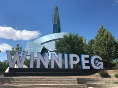 a large sign that says winnipeg in front of some stairs and trees