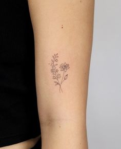 a woman's arm with a small flower tattoo on the left side of her arm