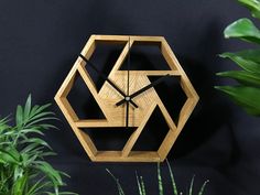 a wooden clock sitting on top of a black wall next to plants and potted plants