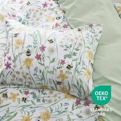 the bedding is made up with flowers and bees on it, along with a green pillow case