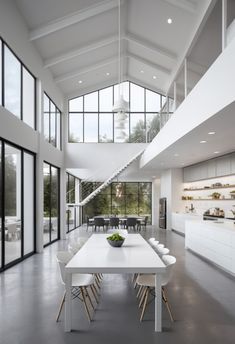 a dining room table with chairs and a bowl of fruit on it in front of large windows