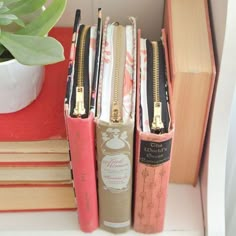 three books are stacked on top of each other in front of a potted plant