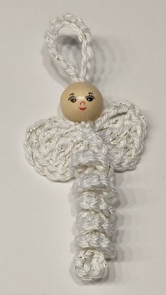 a small white angel ornament hanging from a string on a white background,