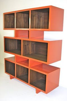 an orange shelf with several compartments on each side and two shelves below it, in front of a white wall