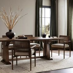 a dining room table with chairs and a vase on the floor in front of it