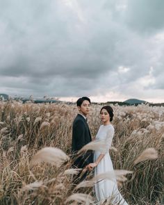 a bride and groom standing in tall grass