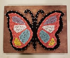 a string art butterfly on a wooden board