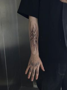 a man's hand with tattoos on his left and right arm, in front of an elevator