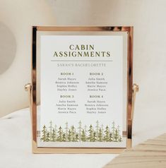 a wooden table with a sign on it that says cabin assignments in gold frame