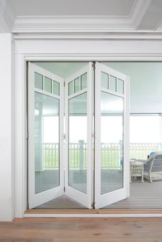 an open white door leading to a deck with chairs and wicker furniture in the background